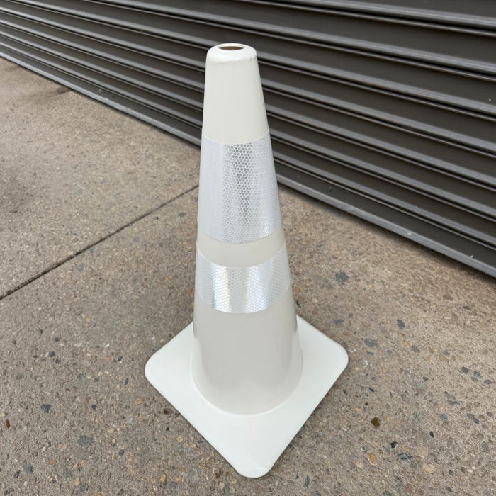 Overhead close-up of a white traffic cone showing its reflective bands.