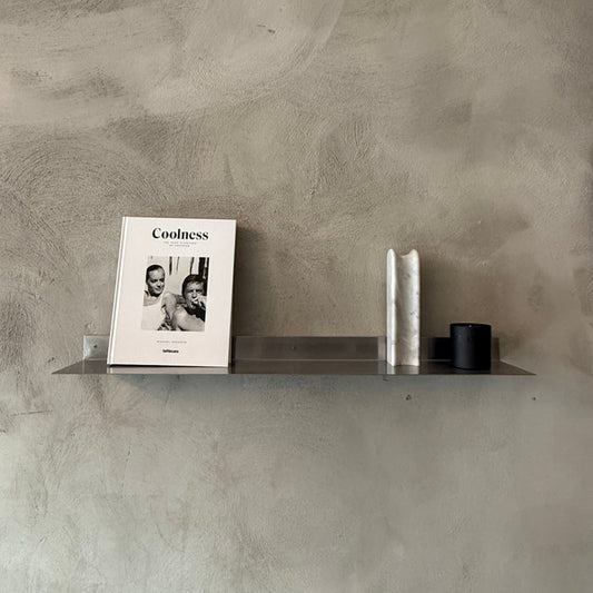 Stainless steel wall shelf displaying a book and small decorative objects.