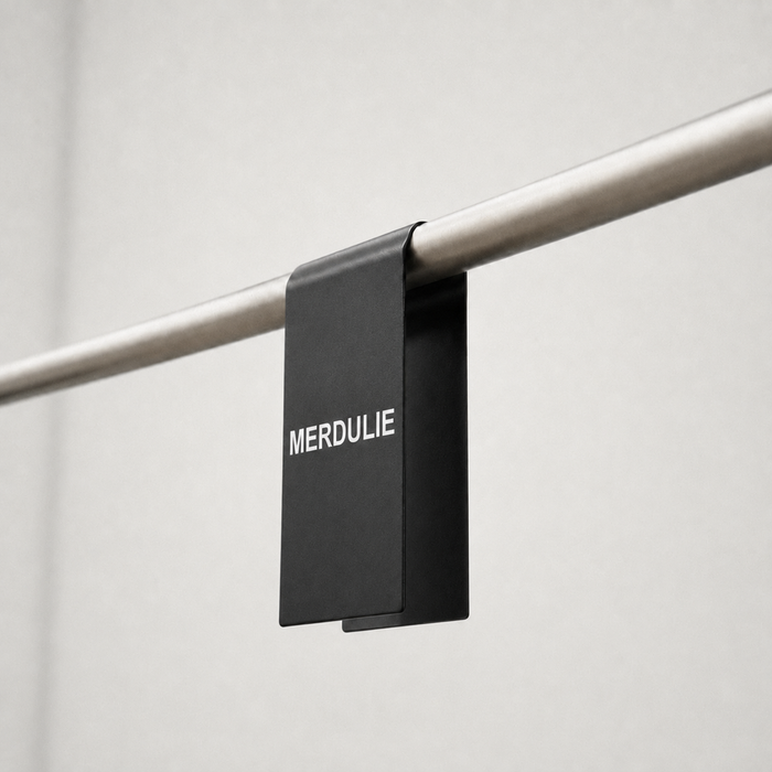 Black clothing rack sign clip with white Merdulié lettering.