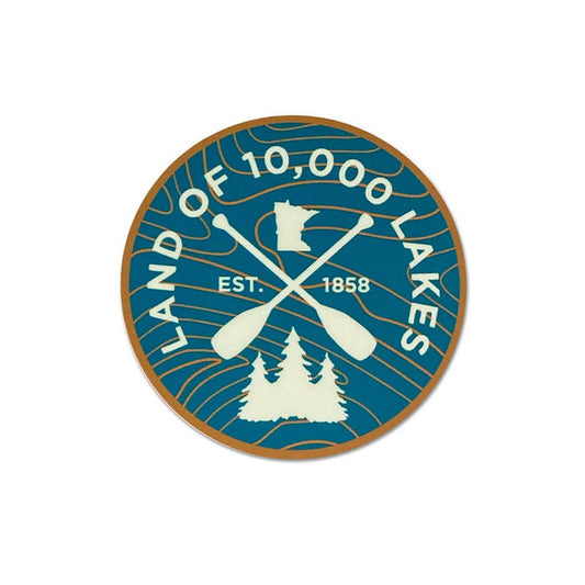 Circular bumper style sticker with 'Land of 10,000 Lakes' text, crossed paddles, and trees on a blue background.
