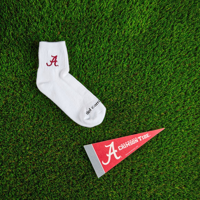 Flat lay of Del Campo Alabama Crimson Tide golf socks with game-day props