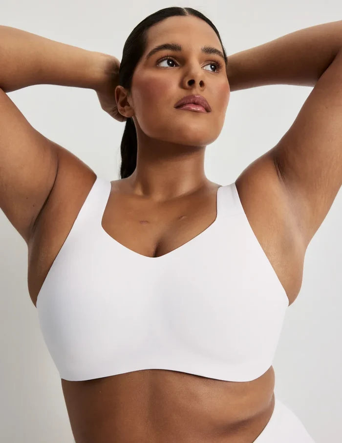 Adiya is a 36C and wearing KNIX L | Front view of model wearing the Catalyst Sports Bra, highlighting the neckline, strap design, and smooth silhouette | White