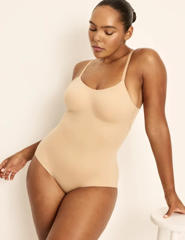 Amber is a 36C, has 46” hips, is 5’10.5” tall and wears a size L  | Front view of model wearing the Customizable Shaper Bodysuit highlighting the coverage and smooth fit | Warm Sand