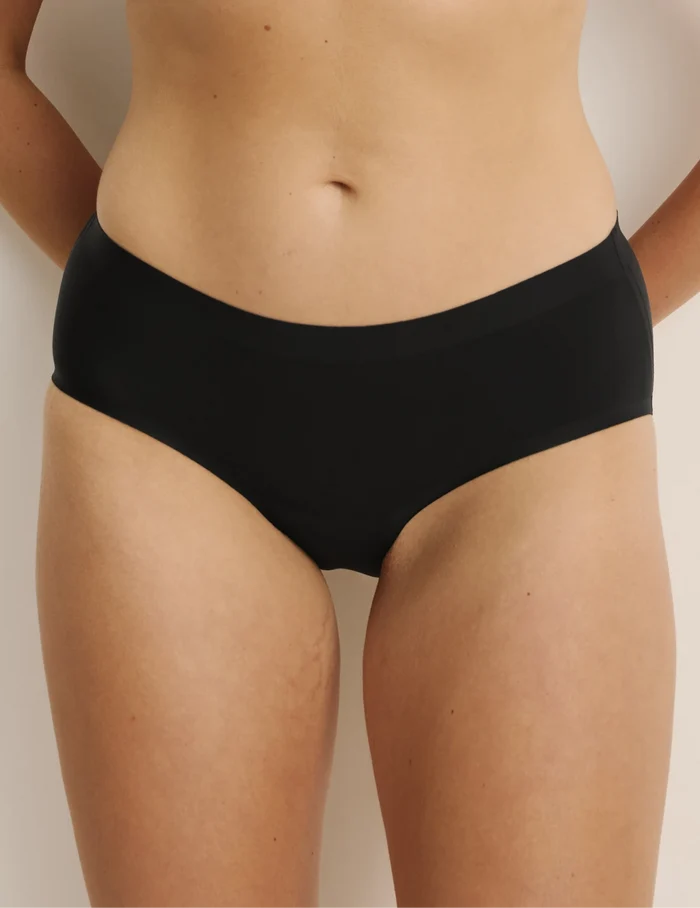 Sarah has 38.5” hips, and wearing KNIX M | Front view of model wearing the Essential No-Show Boyshort highlighting the coverage and smooth fit | Black