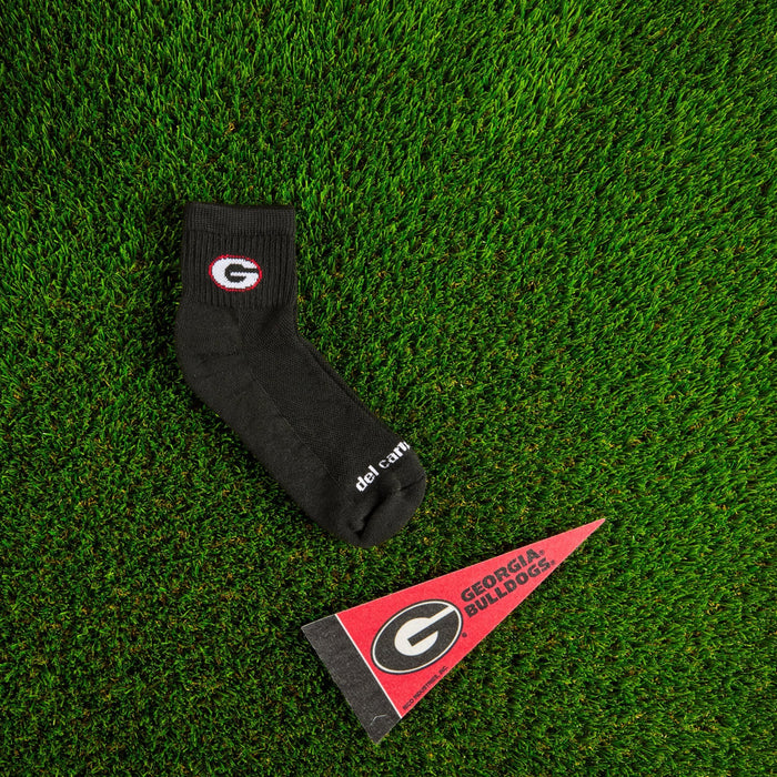 Flat lay of Del Campo Georgia Night Mode golf socks with game-day props