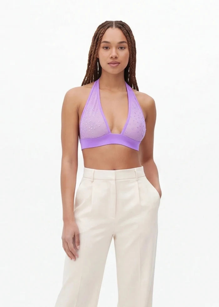Woman wearing a purple top and white pants on a white background