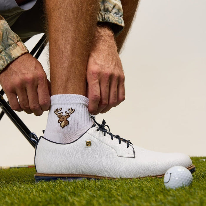 Del Campo Whitetail Deer sock worn with a white golf shoe beside a golf ball on grass