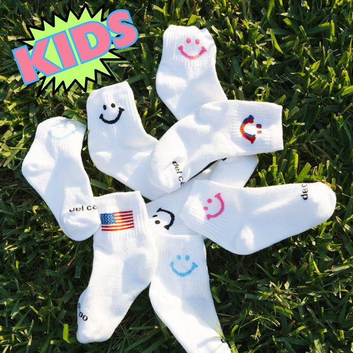 Del Campo Kids Pack golf socks featuring four kids' designs: smiley, blue smiley, pink smiley, and 1776