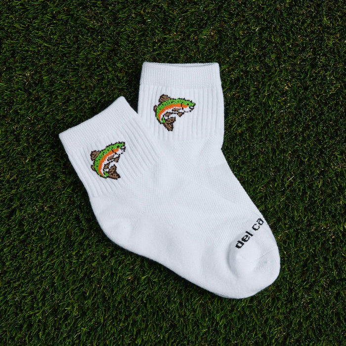 Pair of Del Campo Trout socks with rainbow trout logo laid on grass