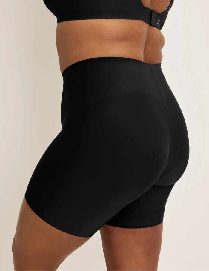 Adiya is wearing KNIX L | Side view of model wearing the Leakproof Contour Thigh Saver® 6”, highlighting the coverage and smooth fit | Black