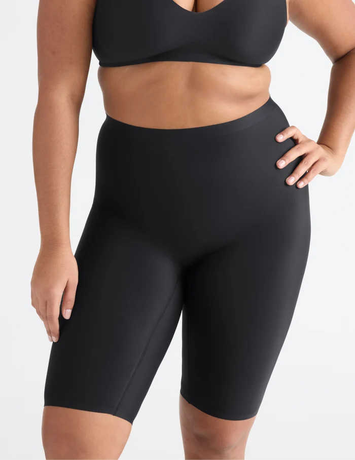 Adiya is wearing KNIX L | Front view of model wearing the Leakproof Thigh Saver® 10”, highlighting the coverage and smooth fit | Black