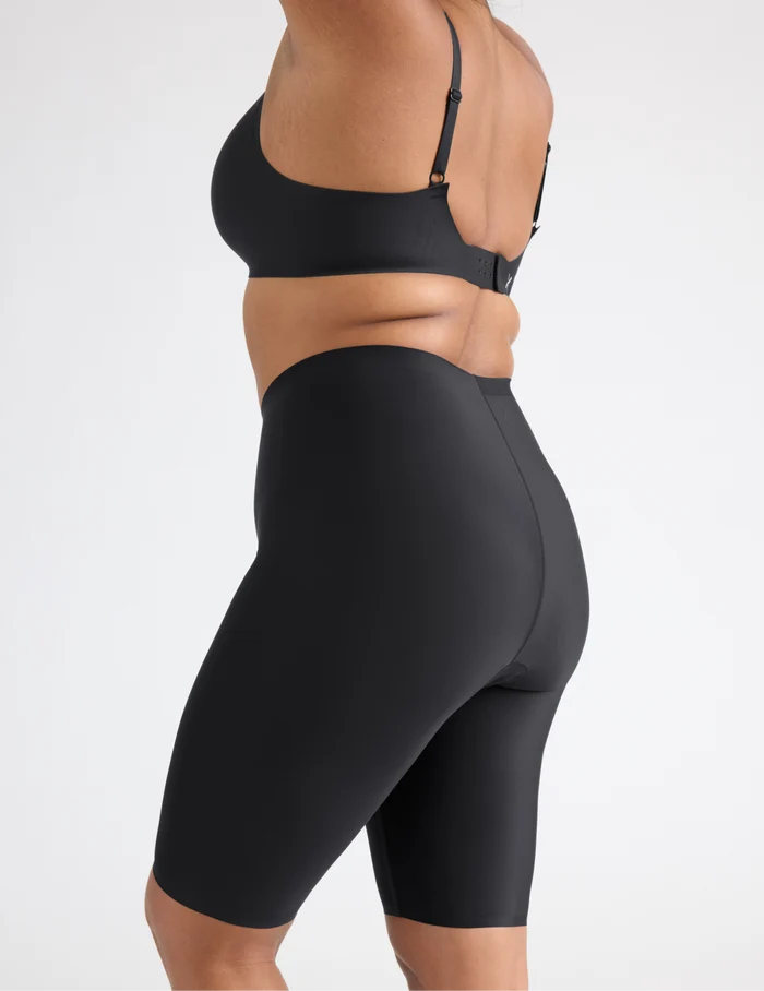 Adiya is wearing KNIX L | Side view of model wearing the Leakproof Thigh Saver® 10”, highlighting the coverage and smooth fit | Black