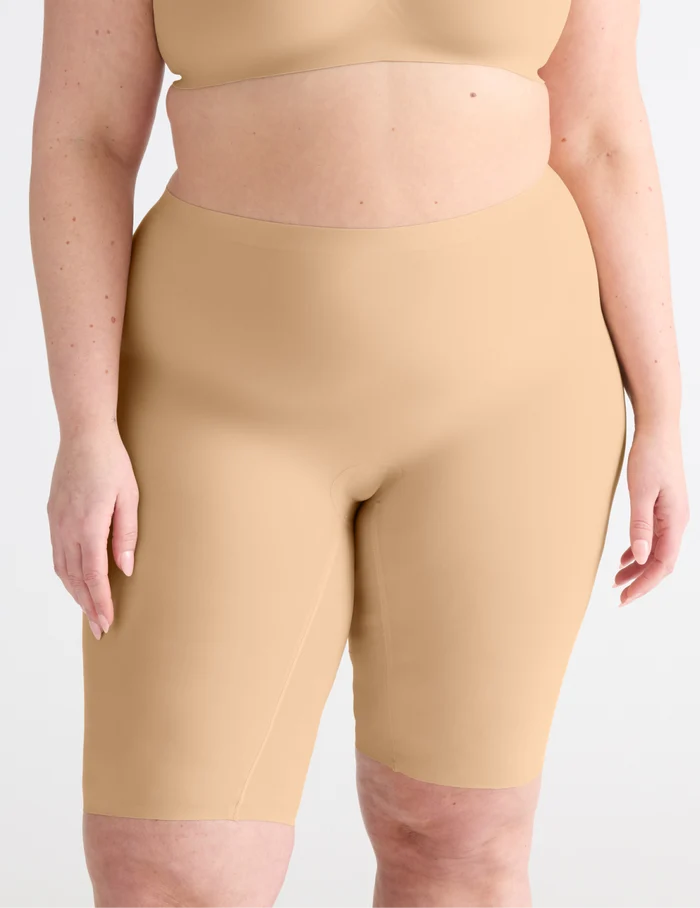 | Front view of model wearing the Leakproof Thigh Saver® 10”, highlighting the coverage and smooth fit | Warm Sand