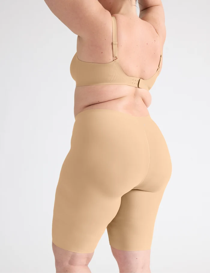 | Side view of model wearing the Leakproof Thigh Saver® 10”, highlighting the coverage and smooth fit | Warm Sand