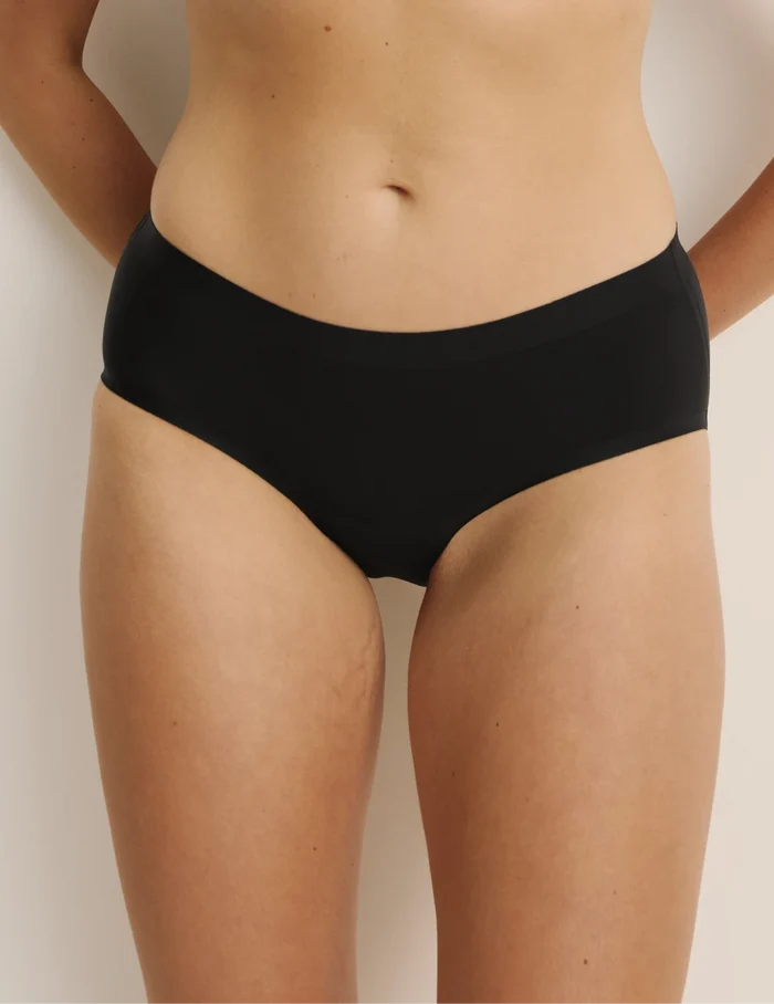 Sarah has 38.5” hips, and wearing KNIX M | Front view of model wearing the Light Leakproof No-Show Boyshort highlighting the coverage and smooth fit | Black