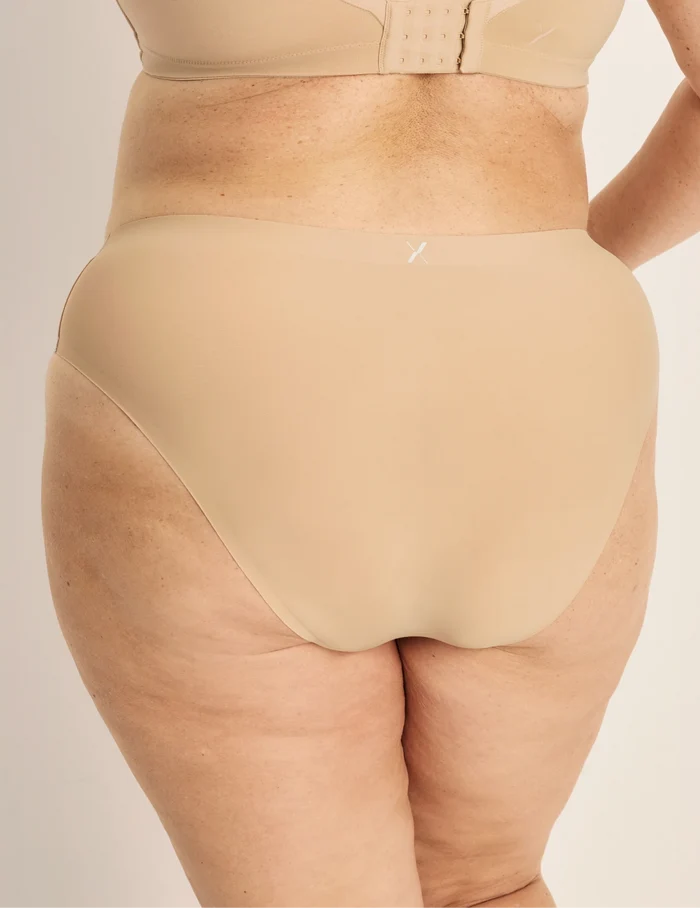 Clementine has 51” hips, and wearing KNIX XXL | Back view of model wearing the Light Leakproof No-Show French Cut highlighting the coverage and smooth fit | Warm Sand