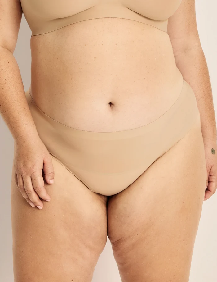 Clementine has 51” hips, and wearing KNIX XXL | Front view of model wearing the Light Leakproof No-Show Thong highlighting the coverage and smooth fit | Warm Sand
