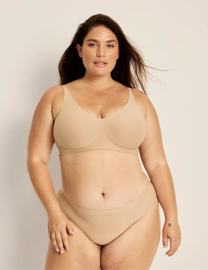 Clementine has 51” hips, and wearing KNIX XXL | Full-body view of model wearing the Light Leakproof No-Show Thong highlighting the coverage and smooth fit | Warm Sand