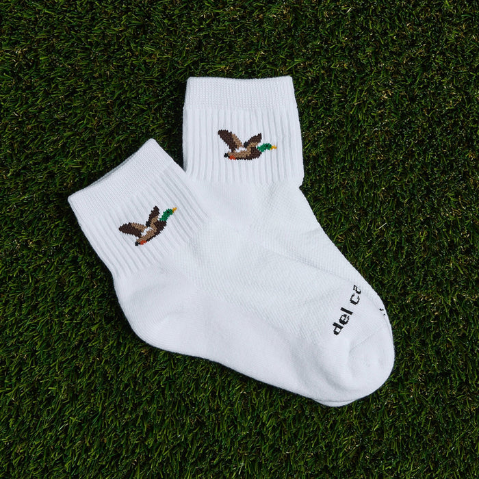 Pair of Del Campo Mallard socks with flying duck logo laid on grass