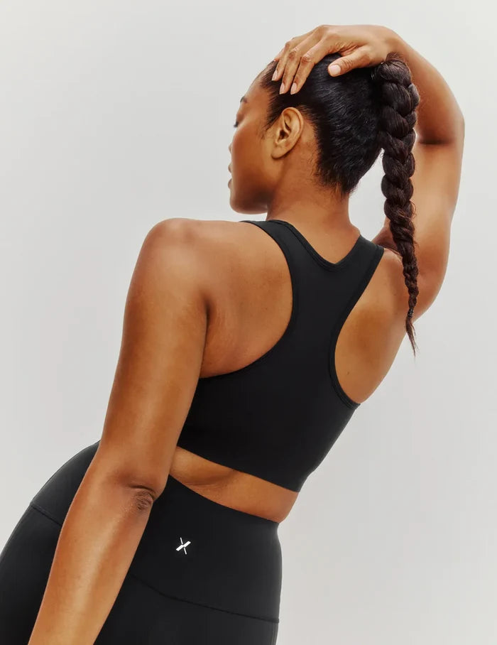 Cassaerea is a 34G and wears a Knix size M++ | Back view of model wearing the Momenta Racerback Sports Bra, highlighting the neckline, strap design, and silhouette | Black