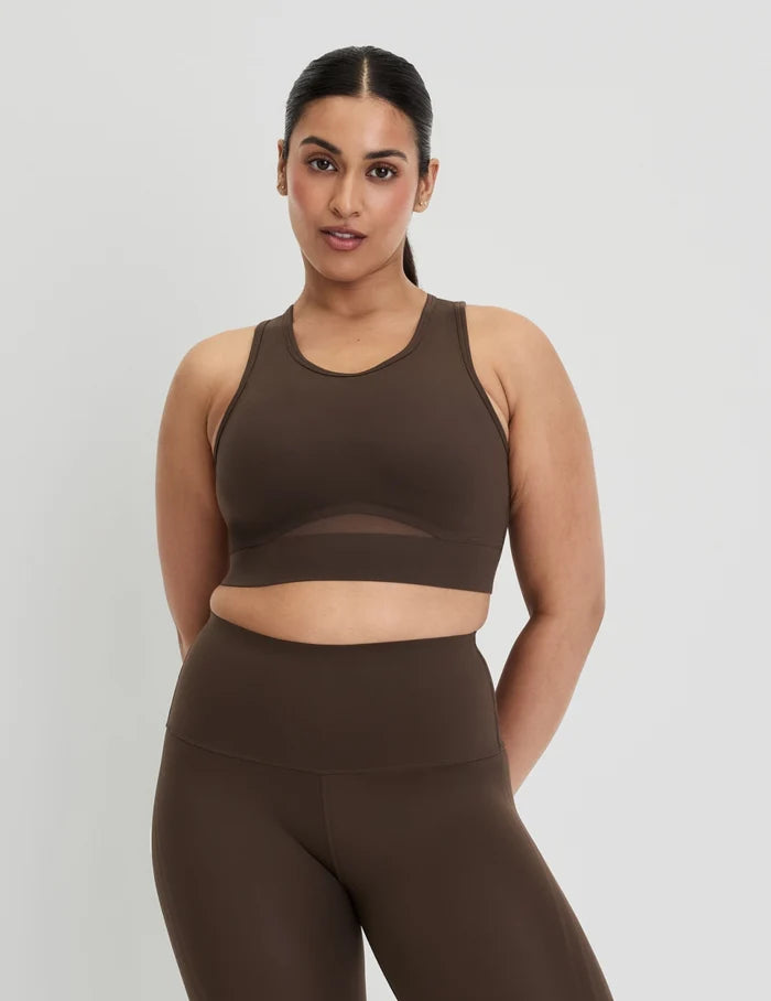 | Front view of model wearing the Momenta Racerback Sports Bra, highlighting the neckline, strap design, and silhouette | Espresso