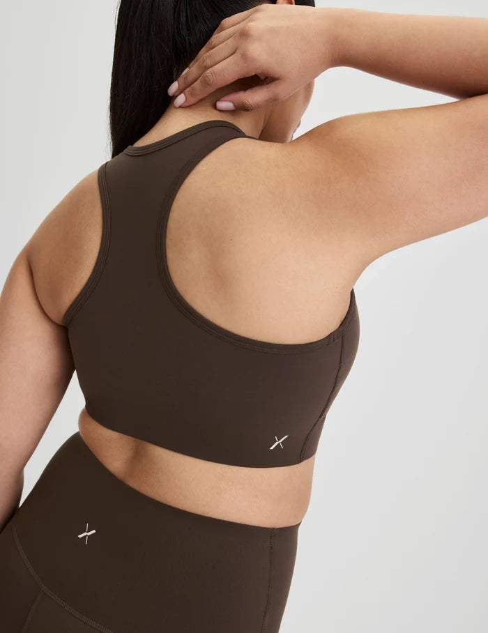 | Back view of model wearing the Momenta Racerback Sports Bra, highlighting the neckline, strap design, and silhouette | Espresso