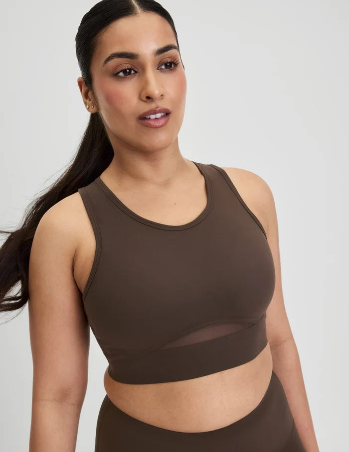 | Front view of model wearing the Momenta Racerback Sports Bra, highlighting the neckline, strap design, and silhouette | Espresso