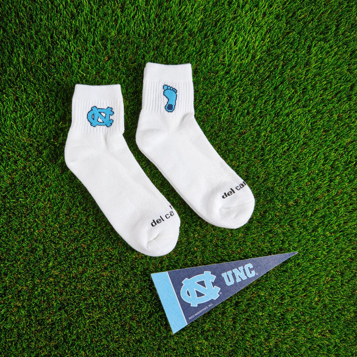 Flat lay of Del Campo North Carolina Pack golf socks with game-day props