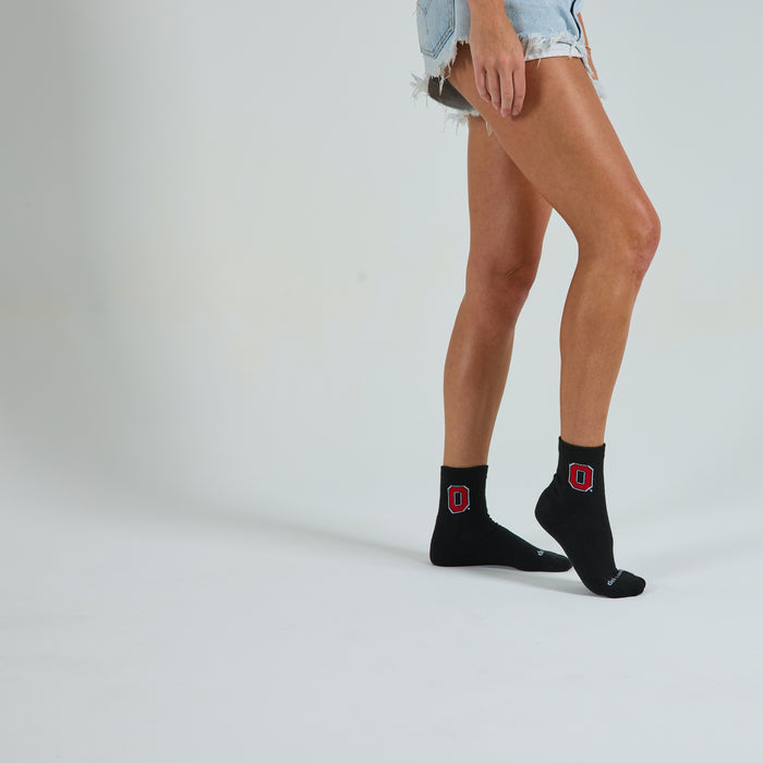 Woman wearing Del Campo Ohio State Night Mode golf socks, studio shot, no shoes
