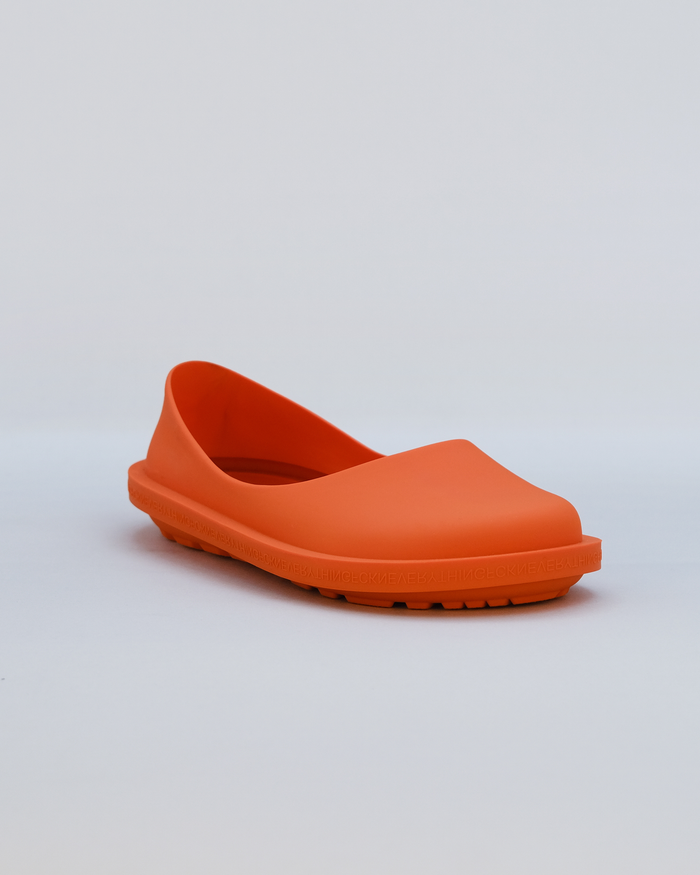 Orange rubber clog with curved upper and textured sole against neutral background.