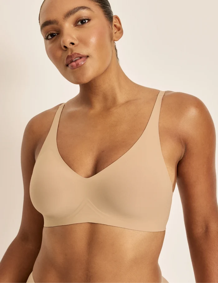 Amber is a 36C and wearing KNIX L | Front view of model wearing the Revolution V-Neck Bra, highlighting the neckline, strap design, and smooth silhouette | Warm Sand