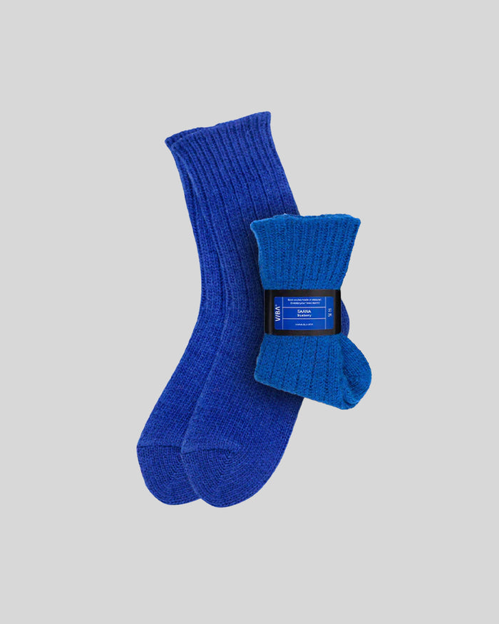 Pair of ribbed knit socks in royal blue and bright blue with black product label band around one sock.