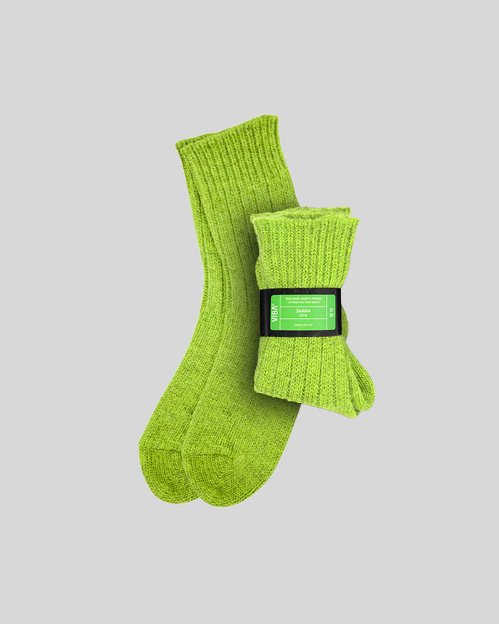 Pair of lime green ribbed knit socks with black label band, displayed flat on gray background.