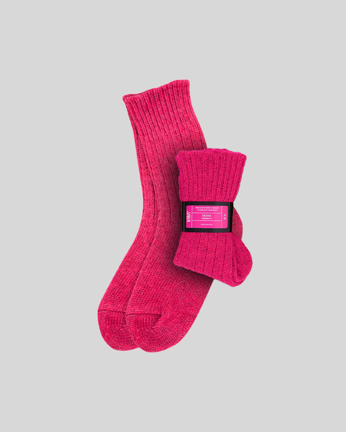 Pair of bright pink ribbed crew socks with product label band around cuff.