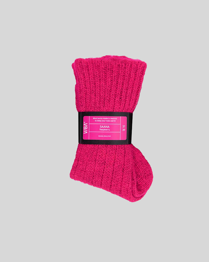 Bright pink cable-knit socks bundled with black SAANA product label band.