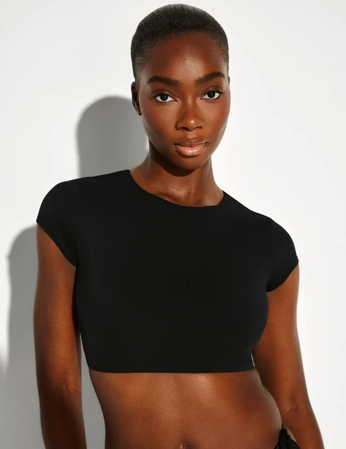 | Front view of model wearing the Sculpt Short Sleeve Swim Top, highlighting the neckline, sleeve design, and silhouette | Black