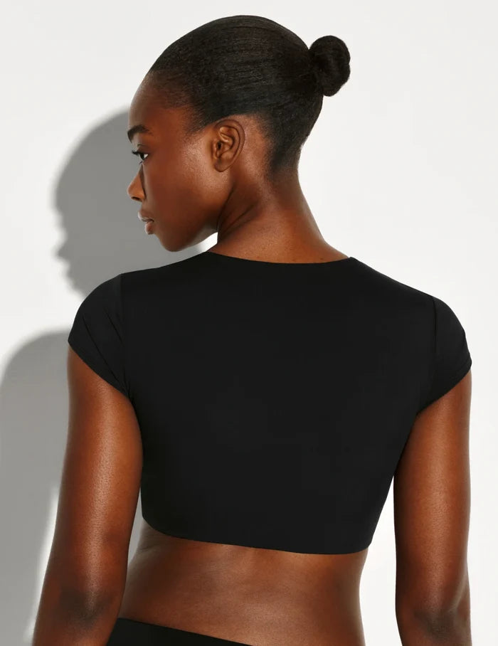| Back view of model wearing the Sculpt Short Sleeve Swim Top, highlighting the neckline, sleeve design, and silhouette | Black