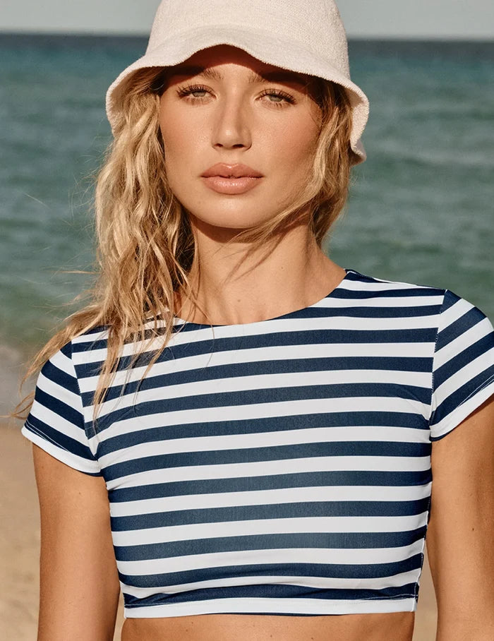 | Front view of model wearing the Sculpt Short Sleeve Swim Top, highlighting the neckline, sleeve design, and silhouette | Nautical Stripe