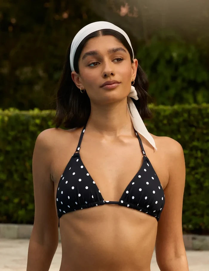 | Front view of model wearing the Sculpt Triangle Bikini Top, highlighting the neckline, strap design, and silhouette | Black with White Polka Dot