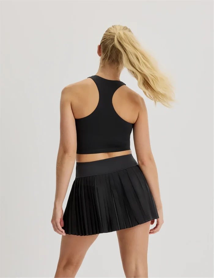 | Back view of model wearing the Teen First Serve Pleated Skort highlighting the coverage and fit | Black