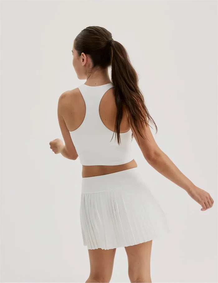 | Back view of model wearing the Teen First Serve Pleated Skort highlighting the coverage and fit | White