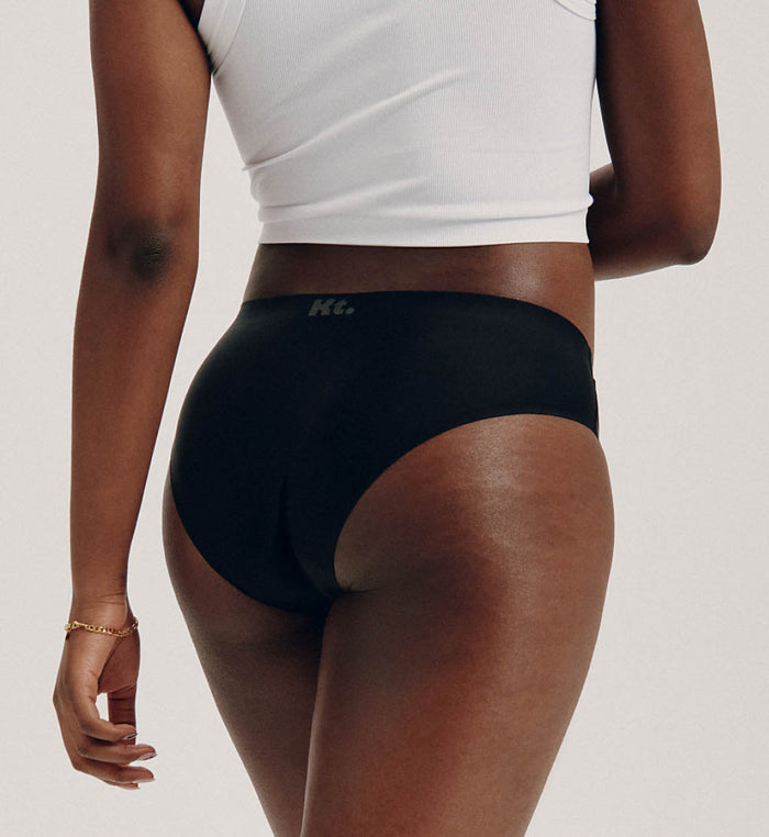 Tracy (she/her) has 37" hips and is wearing a size M | Back view of model wearing the Teen Light Leakproof No-Show Bikini highlighting the coverage and smooth fit | Night Sky/Beige/Black