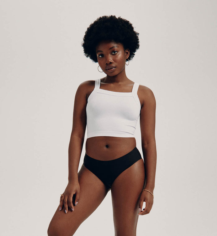 Tracy (she/her) has 37" hips and is wearing a size M | Front view of model wearing the Teen Light Leakproof No-Show Bikini highlighting the coverage and smooth fit | Black