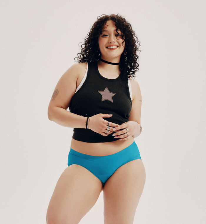 Felixe (she/her) has 44” hips and is wearing a size XL | Front view of model wearing the Teen Light Leakproof No-Show Boyshort highlighting the coverage and smooth fit | Poolside
