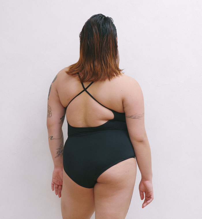 | Back view of model wearing the Teen Period Swim Freestyle One-Piece highlighting the coverage and fit | Black