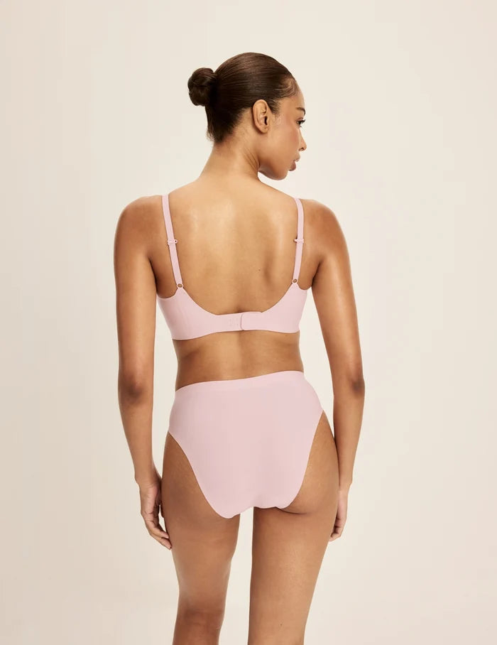 Ashley is a 32DD and wearing KNIX S+ | Back view of model wearing the Revolution Scoop Bra, highlighting the neckline, strap design, and smooth silhouette | Rose Water