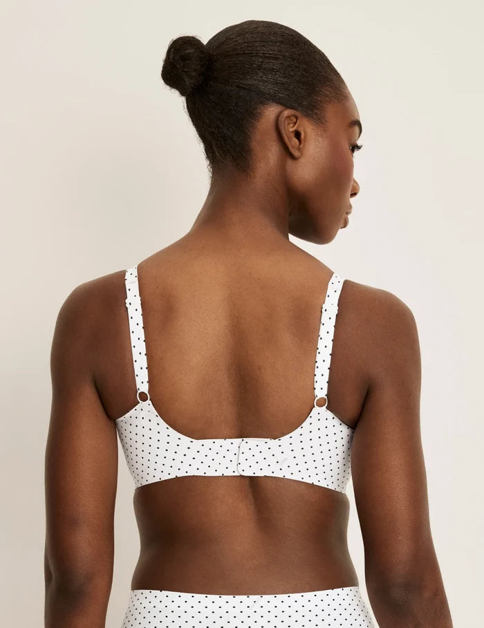 Orlane is a 32DD and wearing KNIX S+ | Back view of model wearing the Revolution V-Neck Bra, highlighting the neckline, strap design, and smooth silhouette | White with Black Polka Dot