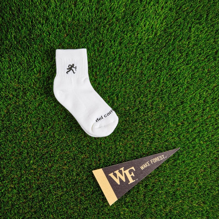 Flat lay of Del Campo Wake Forest Walking Deacon golf socks with game-day props